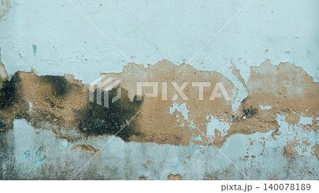 Abstract textured background of a light blue plastered wall with peeling paint and moisture stains 140078189