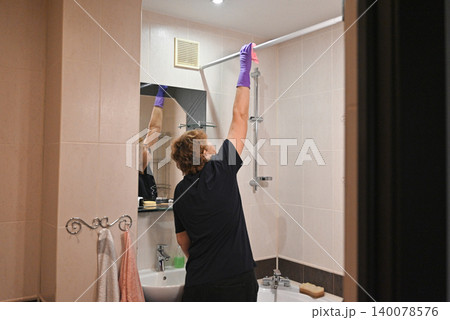 Woman cleaning tiles in a bathroom during daylight 140078576