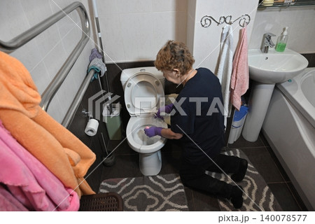 Cleaning the toilet in a small bathroom during the day Cleaning the toilet in a small bathroom during the day 140078577