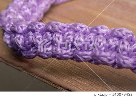 Closeup of purple braided rope showcasing woven fiber texture craftsmanship durability detailed pattern wooden surface Closeup of purple braided rope showcasing woven fiber texture craftsmanship durability detailed pattern wooden surface 140079452