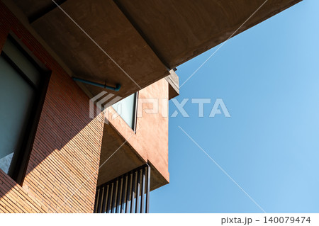 Modern brick building facade geometric architecture balcony window viewed from below against clear blue sky Urban design construction background Modern brick building facade geometric architecture balcony window viewed from below against clear blue sky Urban design construction background 140079474