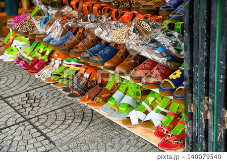 Rows of colorful handmade leather sandals and shoes displayed on shelves at an outdoor street market in Hoi An Vietnam 140079540