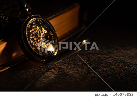 Antique pocket watch, a beautiful low-key scene of a wonderful pocket watch illuminated by a sliver of light from a window, selective focus. Antique pocket watch, a beautiful low-key scene of a wonderful pocket watch illuminated by a sliver of light from a window, selective focus. 140079852