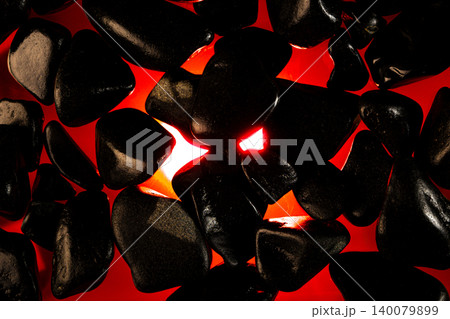Incandescent stone texture, a dark stone texture with an ember effect underneath and a dark background, selective focus. Incandescent stone texture, a dark stone texture with an ember effect underneath and a dark background, selective focus. 140079899