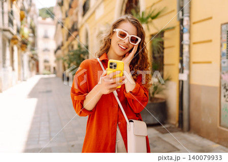 Attractive woman tourist walking on city street using smartphone. Travel, blogging lifestyle concept Attractive woman tourist walking on city street using smartphone. Travel, blogging lifestyle concept 140079933