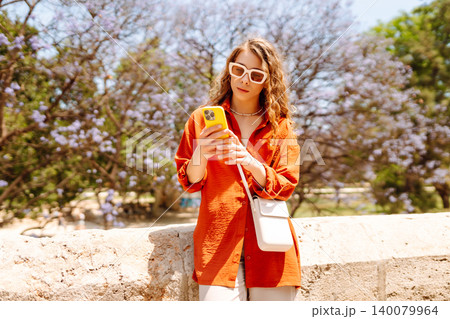 Young woman using smart phone and smile with walking in city outdoor. Business, blogging concept. 140079964