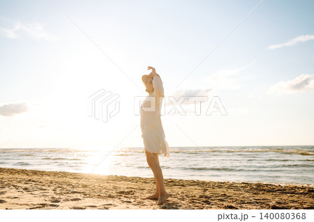 Young woman walking by beach at golden sunset - Female tourist on summer vacation. Young woman walking by beach at golden sunset - Female tourist on summer vacation. 140080368