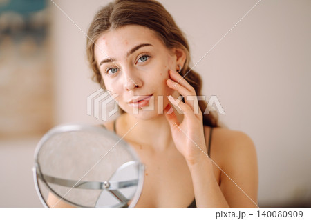Young woman with problem skin looking into mirror. Inflammation on face, problem skin. Beauty care. Young woman with problem skin looking into mirror. Inflammation on face, problem skin. Beauty care. 140080909