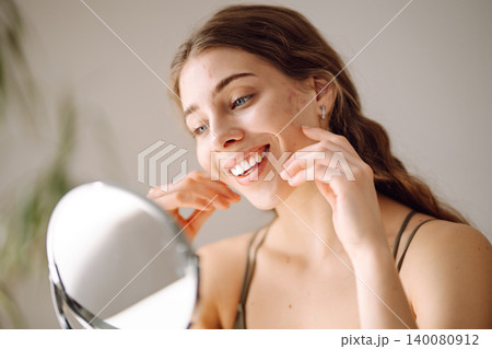 Young woman with problem skin looking into mirror. Inflammation on face, problem skin. Beauty care. 140080912