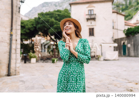 Happy female tourist in beautiful dress walking in the street of the city. Fashion style. 140080994