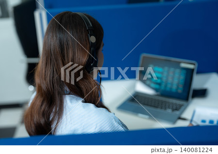 Friendly smiling female call-center agent with headset working on support hotline in office. Friendly smiling female call-center agent with headset working on support hotline in office. 140081224