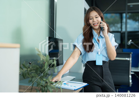 Consulent speaking to mobile cellphone at home office. women speak with remote clients using phone. Laptop on the desk. Consulent speaking to mobile cellphone at home office. women speak with remote clients using phone. Laptop on the desk. 140081226