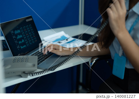 Consulent speaking to mobile cellphone at home office. women speak with remote clients using phone. Laptop on the desk. 140081227