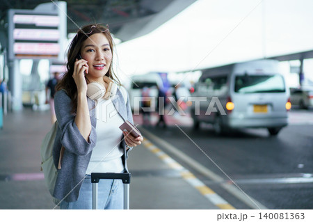 Young Asian traveler using smartphone to call taxi or bus at airport Young Asian traveler using smartphone to call taxi or bus at airport 140081363