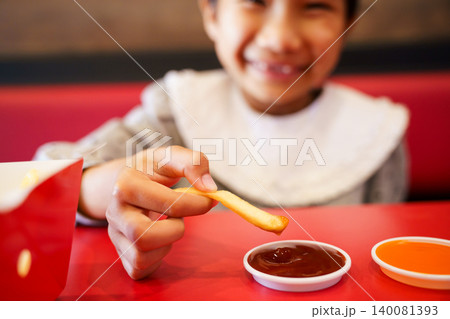 Asian girl dipping french fries into sauce at restaurant Asian girl dipping french fries into sauce at restaurant 140081393
