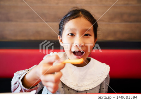 Asian girl dipping french fries into sauce at restaurant Asian girl dipping french fries into sauce at restaurant 140081394