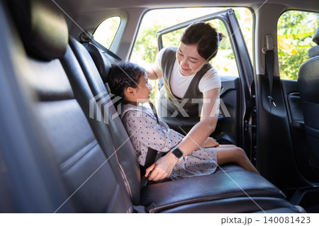 Asian mother fastening seat belt for her daughter in car Asian mother fastening seat belt for her daughter in car 140081423