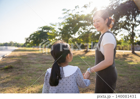 Asian mother and daughter holding hands walking in the park Asian mother and daughter holding hands walking in the park 140081431