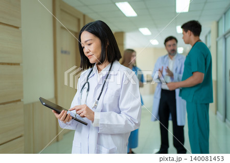 Asian female doctor using digital tablet in hospital corridor Asian female doctor using digital tablet in hospital corridor 140081453