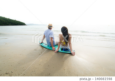 Young Couple Sitting on Surfboard Watching the Ocean at Beach Young Couple Sitting on Surfboard Watching the Ocean at Beach 140081598