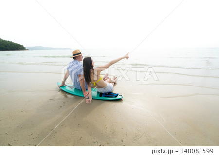 Young Couple Sitting on Surfboard Watching the Ocean at Beach Young Couple Sitting on Surfboard Watching the Ocean at Beach 140081599