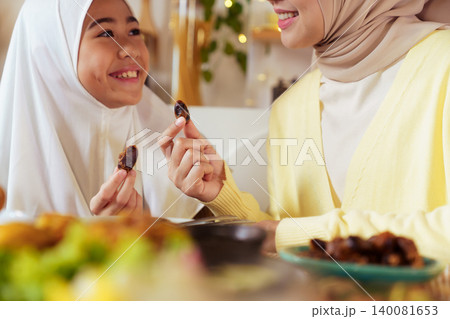 Muslim Mother and Daughter Breaking Fast with Dates in Ramadan 140081653