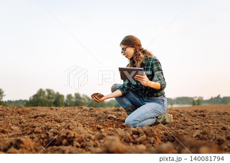 Farmer woman with a digital tablet holds black soil in her hands. Concept of technology, ecology. Farmer woman with a digital tablet holds black soil in her hands. Concept of technology, ecology. 140081794