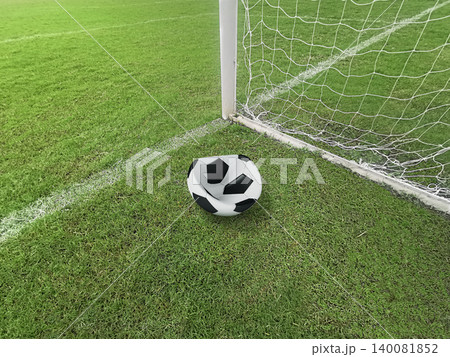 Deflated soccer ball on green grass field near the goal post, failure or missed opportunity concept 140081852