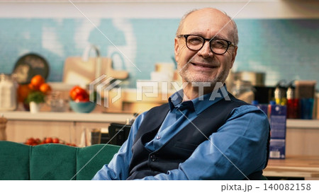 Portrait of male pensioner with candid smile resting at home on couch, domestic life alone with relaxation and tranquility. Senior man feeling peaceful during quiet retirement moments, aging. Portrait of male pensioner with candid smile resting at home on couch, domestic life alone with relaxation and tranquility. Senior man feeling peaceful during quiet retirement moments, aging. 140082158