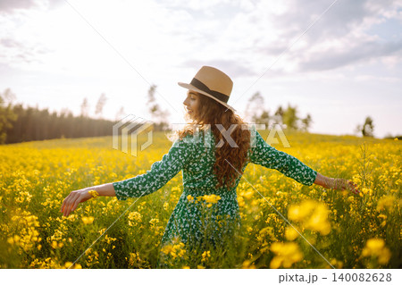 Young woman walking flowering field gently touch yellow flowers. Summer landscape. Young woman walking flowering field gently touch yellow flowers. Summer landscape. 140082628
