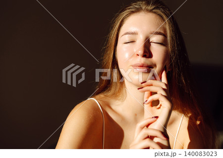 Young woman enjoying sunlight while relaxing indoors during daytime. Concept of naturalness, beauty Young woman enjoying sunlight while relaxing indoors during daytime. Concept of naturalness, beauty 140083023