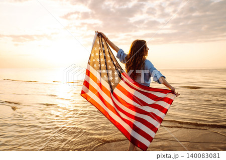 Young woman with American flag on beach. Patriotic holiday. Independence Day concept Young woman with American flag on beach. Patriotic holiday. Independence Day concept 140083081