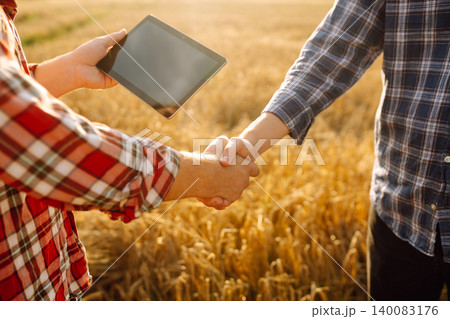 Handshake, joint work of farmers. Two farmers making agreement with handshake in wheat field. Handshake, joint work of farmers. Two farmers making agreement with handshake in wheat field. 140083176