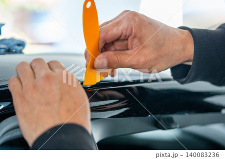 A car wrapping specialist applies a polyurethane film to the car. Detailer PPF 140083236