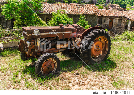 Rupit, Spain, 20 May 2026: Rustic vintage tractor in Rupit village, Catalonia, Spain, parked beside traditional stone houses, illustrating rural heritage, agricultural history and countryside life 140084811