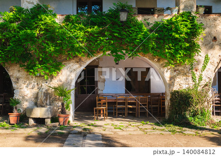 Historic Mediterranean courtyard with stone arches and rustic outdoor dining area 140084812