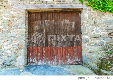 Weathered wooden garage door in rustic stone building facade of medieval Rupit village, Catalonia, Spain Weathered wooden garage door in rustic stone building facade of medieval Rupit village, Catalonia, Spain 140084818