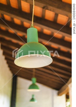 Vintage green pendant lamps hanging beneath wooden ceiling in rustic countryside interior Vintage green pendant lamps hanging beneath wooden ceiling in rustic countryside interior 140084840