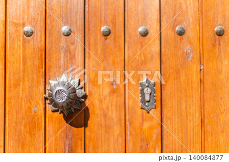 Decorative antique door handle and keyhole on traditional wooden entrance door, close up architectural detail Decorative antique door handle and keyhole on traditional wooden entrance door, close up architectural detail 140084877