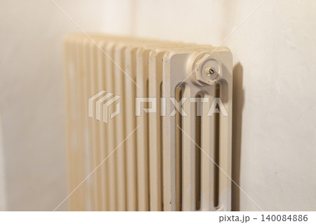 Vintage cast iron radiator mounted on wall in traditional countryside house interior Vintage cast iron radiator mounted on wall in traditional countryside house interior 140084886