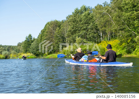 Family paddling the Vuoksa kayak along river, outdoor summer teamwork, shared adventure, water sport, nature tourism. Family paddling the Vuoksa kayak along river, outdoor summer teamwork, shared adventure, water sport, nature tourism. 140085156