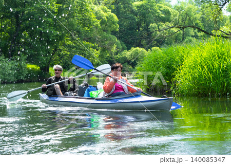 Older married couple kayaking on a Varzuga kayak, enjoying water adventure and outdoor activity, mature tourism. 140085347