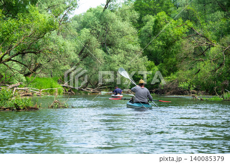 Man paddling kayak alone, exploring wild river nature, solo active adventure, scenic summer water tourism. 140085379