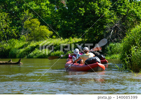 Family kayaking in inflatable boat through green riverside, summer water tourism, outdoor adventure, fun group leisure and exploration. Family kayaking in inflatable boat through green riverside, summer water tourism, outdoor adventure, fun group leisure and exploration. 140085399