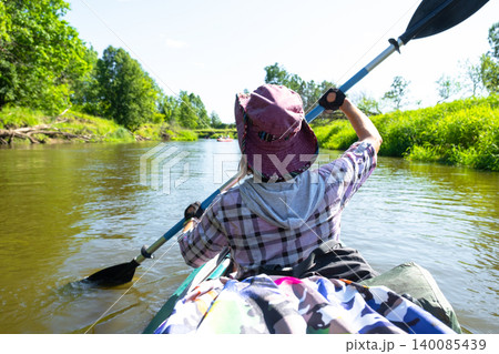 Female kayaker with paddle, enjoying summer river, outdoor sport tourism, adventure recreational experience and gear in use. 140085439