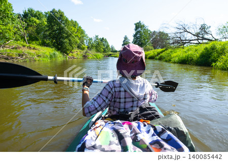 Woman kayaking on calm river, back view, outdoor water activity, summer touring, recreational paddling, sports gear detail. Woman kayaking on calm river, back view, outdoor water activity, summer touring, recreational paddling, sports gear detail. 140085442