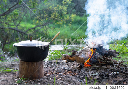 Pot with meal on campfire, classic hiking dinner at rest, outdoor cooking experience on nature trip. Pot with meal on campfire, classic hiking dinner at rest, outdoor cooking experience on nature trip. 140085602