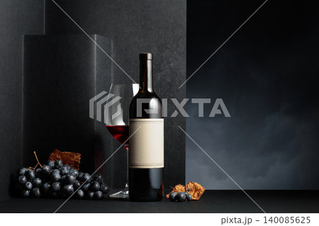 Red wine and blue grapes with dried up vine leaves on a black background. 140085625