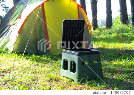Portable toilet near tent at campsite, field use for outdoor hygiene, travel convenience, tourism, and nature application. Portable toilet near tent at campsite, field use for outdoor hygiene, travel convenience, tourism, and nature application. 140085707