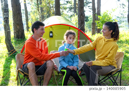 Family applying mosquito repellent at campsite, parenting and child care, focus on allergy, disease prevention, safety, healthy outdoor summer moment. Family applying mosquito repellent at campsite, parenting and child care, focus on allergy, disease prevention, safety, healthy outdoor summer moment. 140085905